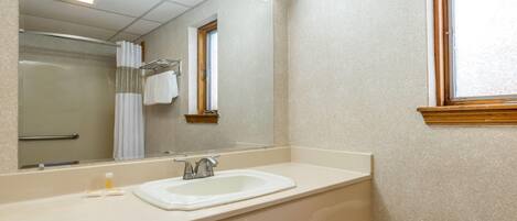 A bathroom with a sink, mirror, and shower.