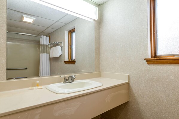 A bathroom with a sink, mirror, and shower. - Days Inn by Wyndham Vineland (Vineland)