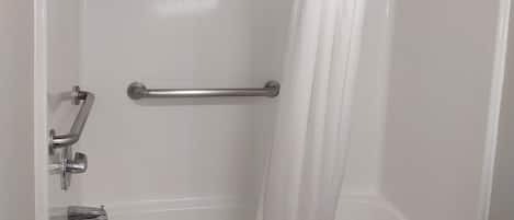 A bathroom with a bathtub, a shower curtain, and a toilet.