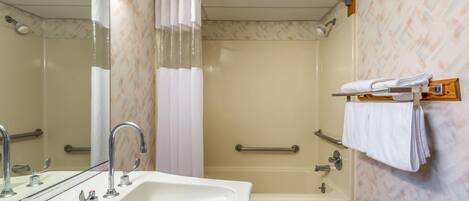 Un baño con lavamanos, espejo, ducha y bañera.