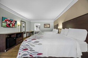 Habitación de hotel con una cama grande, un escritorio con televisión de pantalla plana, microondas y cómoda.