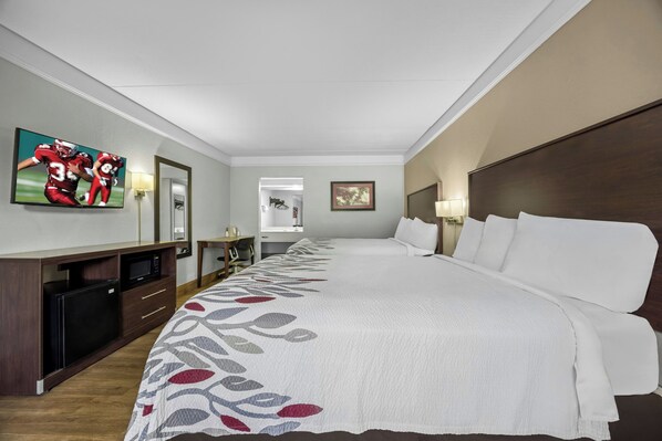 A hotel room with a large bed, a desk with a flat-screen TV, a microwave, and a dresser. - Red Roof Inn & Suites Clinton, TN (Clinton)