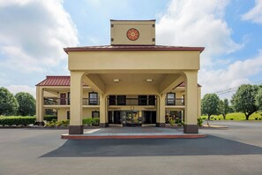 A two-story building with a central entrance, a clock on the roof, and a landscaped area in front. - Red Roof Inn & Suites Clinton, TN (Clinton)