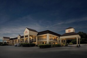 A hotel with multiple buildings, a covered parking area, and a well-maintained landscape. - Red Roof Inn & Suites Clinton, TN (Clinton)