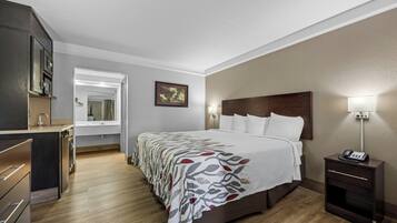 A hotel room with a bed, bedside table, lamp, and a mirror.