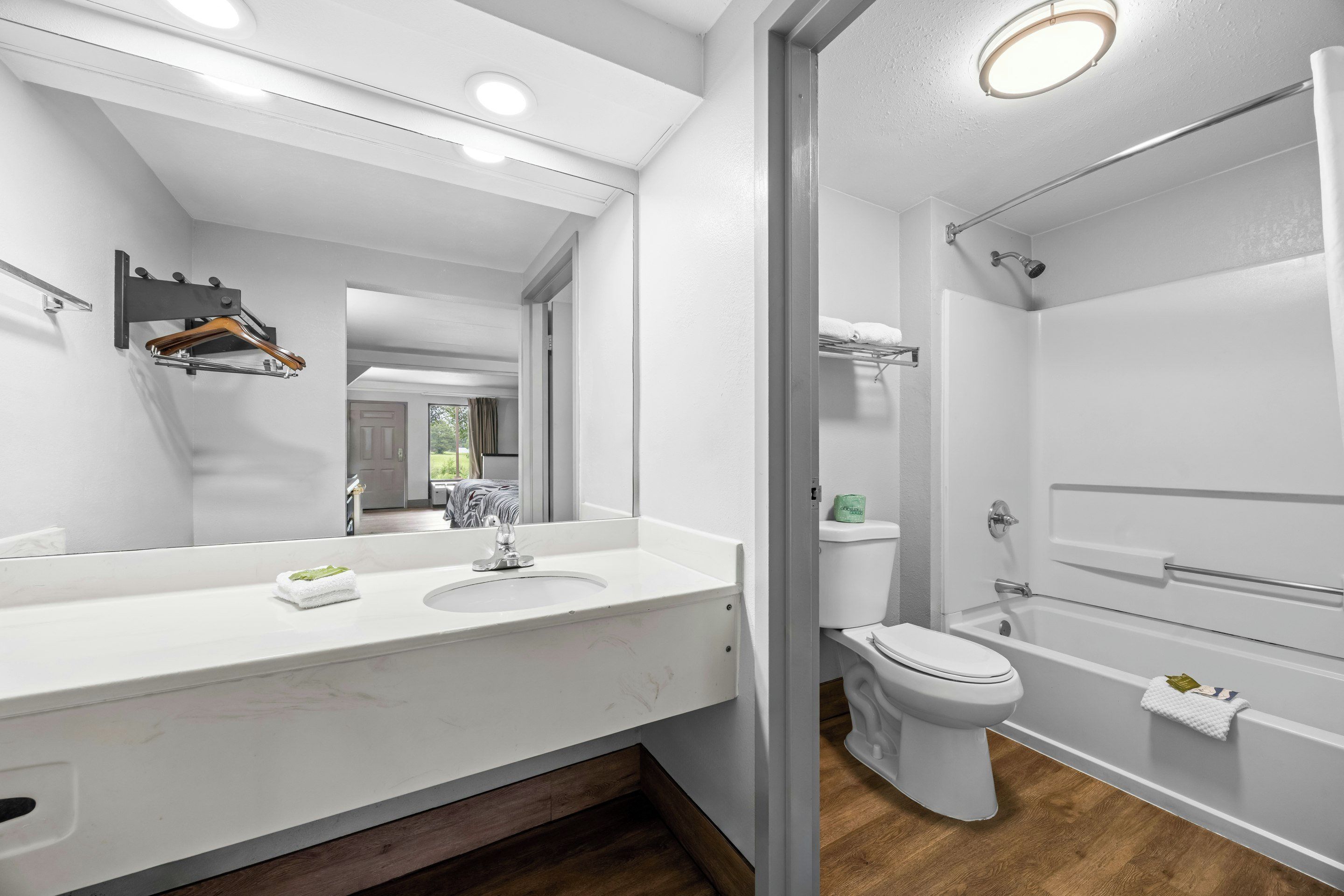 A modern bathroom with a white vanity, a large mirror, a toilet, and a shower area.