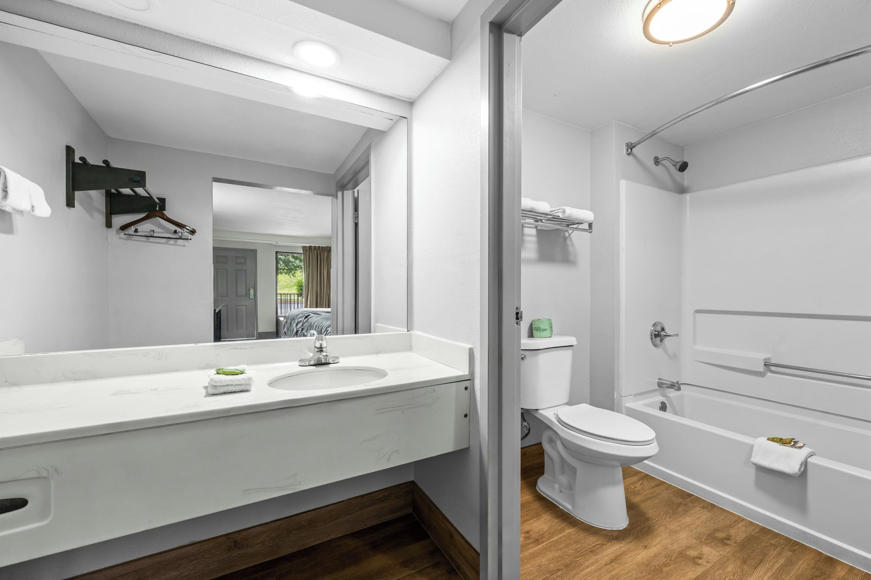 A modern bathroom with a white vanity, a sink, a mirror, a toilet, and a shower area.