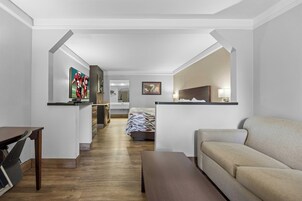 Habitación de hotel con cama, sofá, escritorio y televisor.