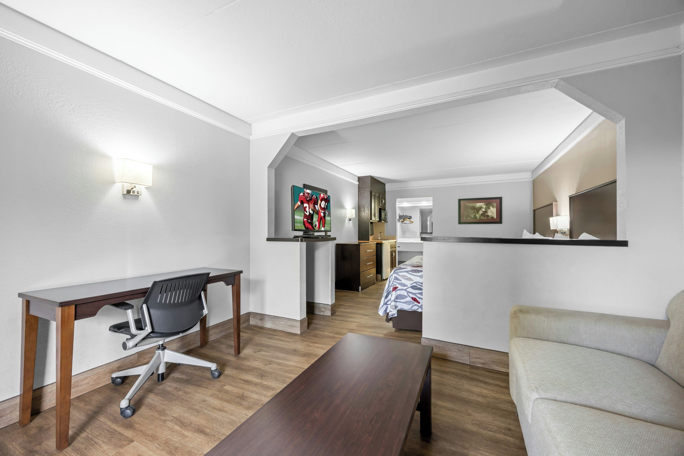 A modern hotel room with a desk, office chair, sofa, and a bed.