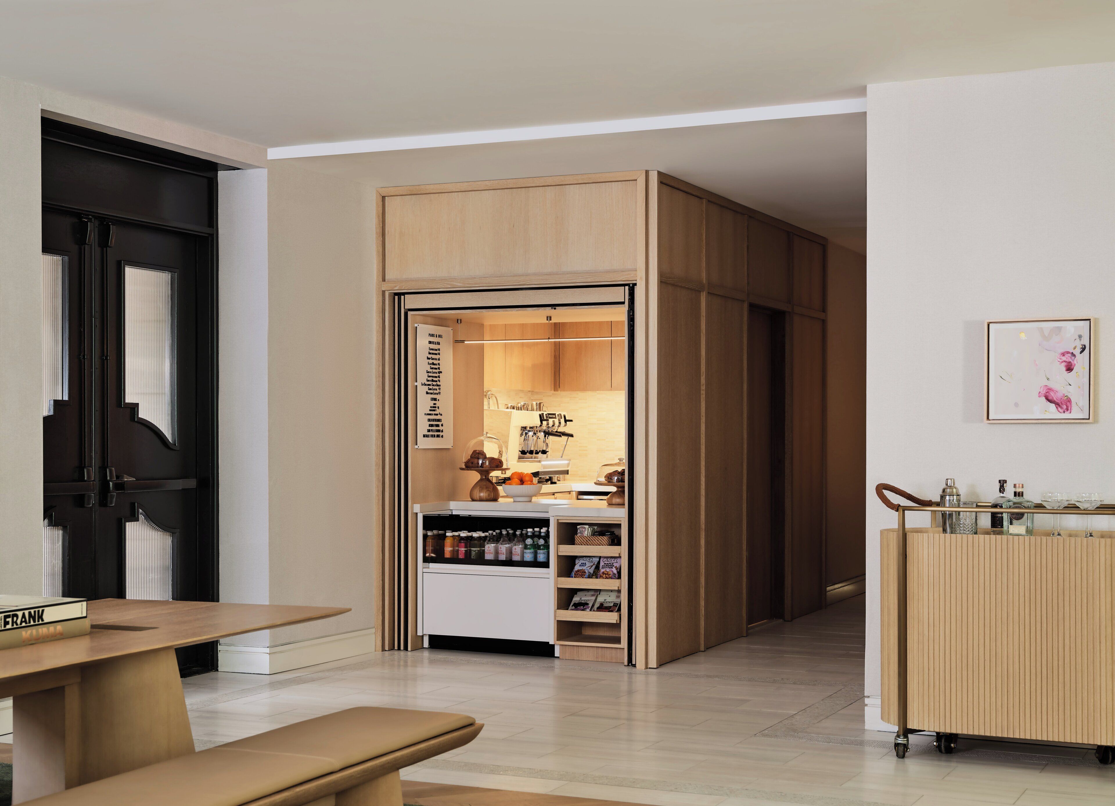 A modern interior with a wooden cabinet, a white shelf unit, and a dining area with a table and bench.