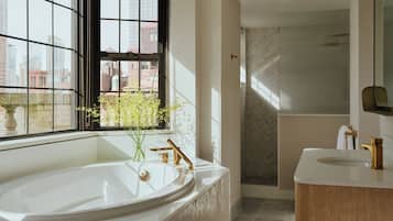A modern bathroom with a freestanding bathtub, a vanity with a mirror, and a shower area.