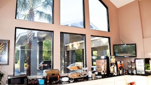 Una cocina con ventanas amplias, microondas, tostadora, cafetera y refrigerador.