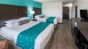 Una habitación de hotel con dos camas, un escritorio, una silla y un televisor.