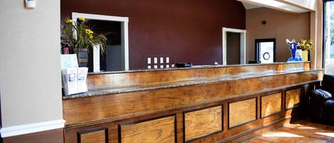 A reception area with a wooden counter, a potted plant, and a framed picture on the wall.