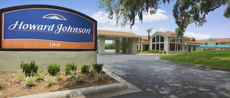 A Howard Johnson Inn sign with a clear view of the building entrance and surrounding landscaping.