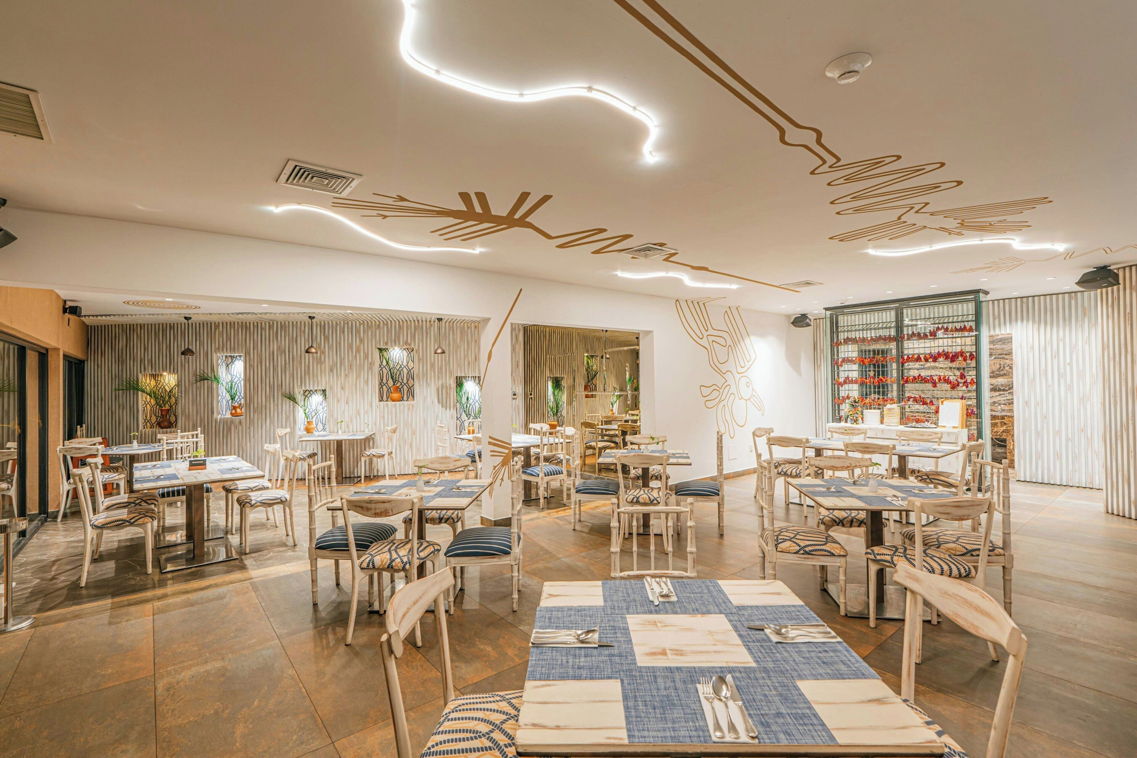 Un restaurant spacieux, doté de meubles en bois, d’un design moderne au niveau du plafond et offrant différents types d’aménagements pour s’asseoir.