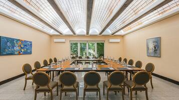 Un salón de conferencias con una larga mesa, sillas y ventanas amplias.