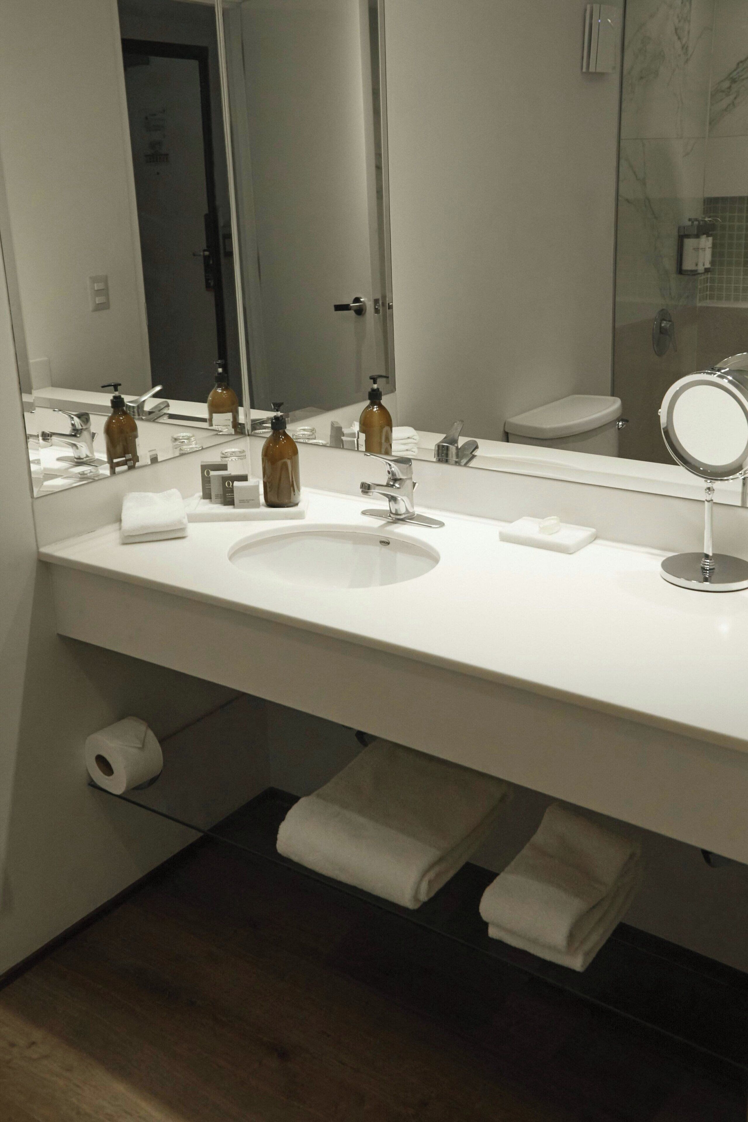 A bathroom with a white sink, a mirror, and a toilet.
