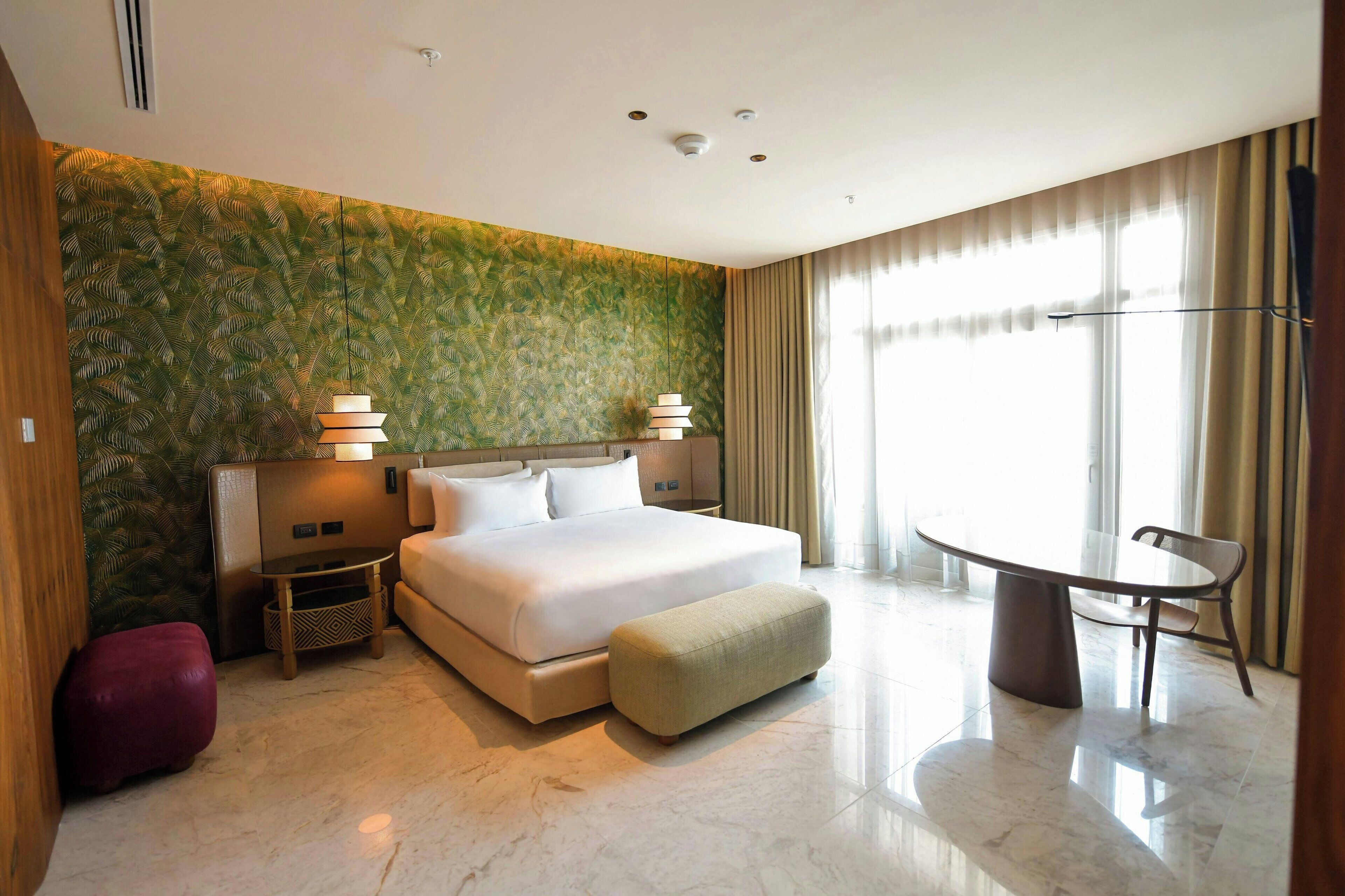 A hotel room with a bed, bedside tables, a table, and a chair.