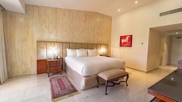 A spacious bedroom with a large bed, bedside tables, a bench, and a red artwork on the wall.