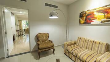 A living room with a striped sofa, a vintage armchair, and a floor lamp.