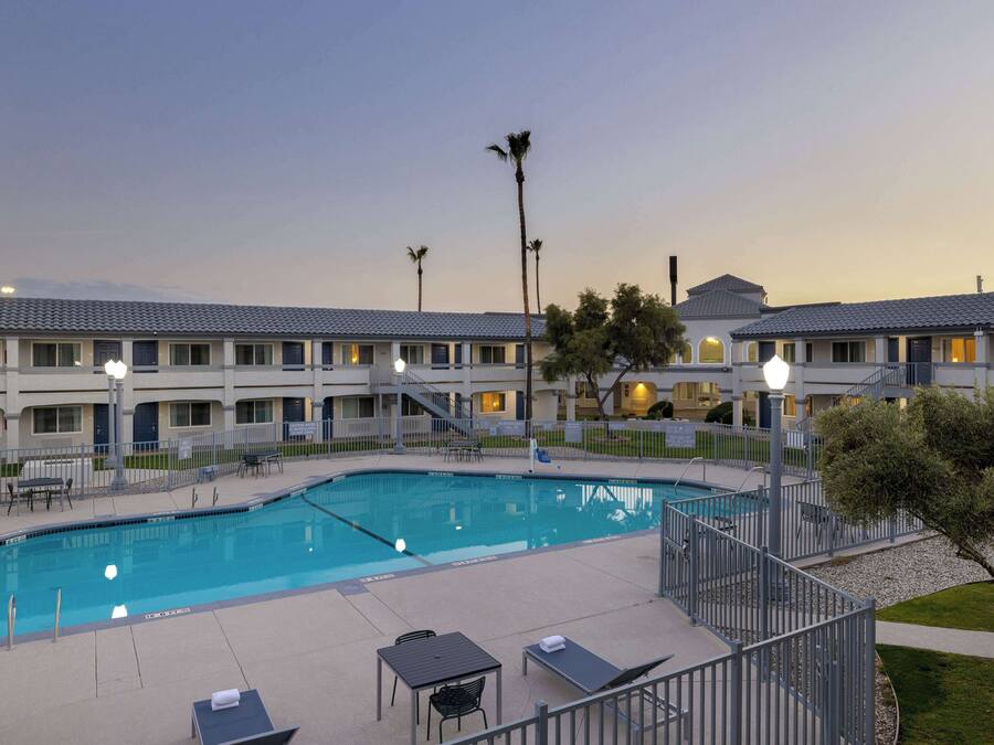 A hotel with a swimming pool, outdoor seating, and a well-lit building facade.