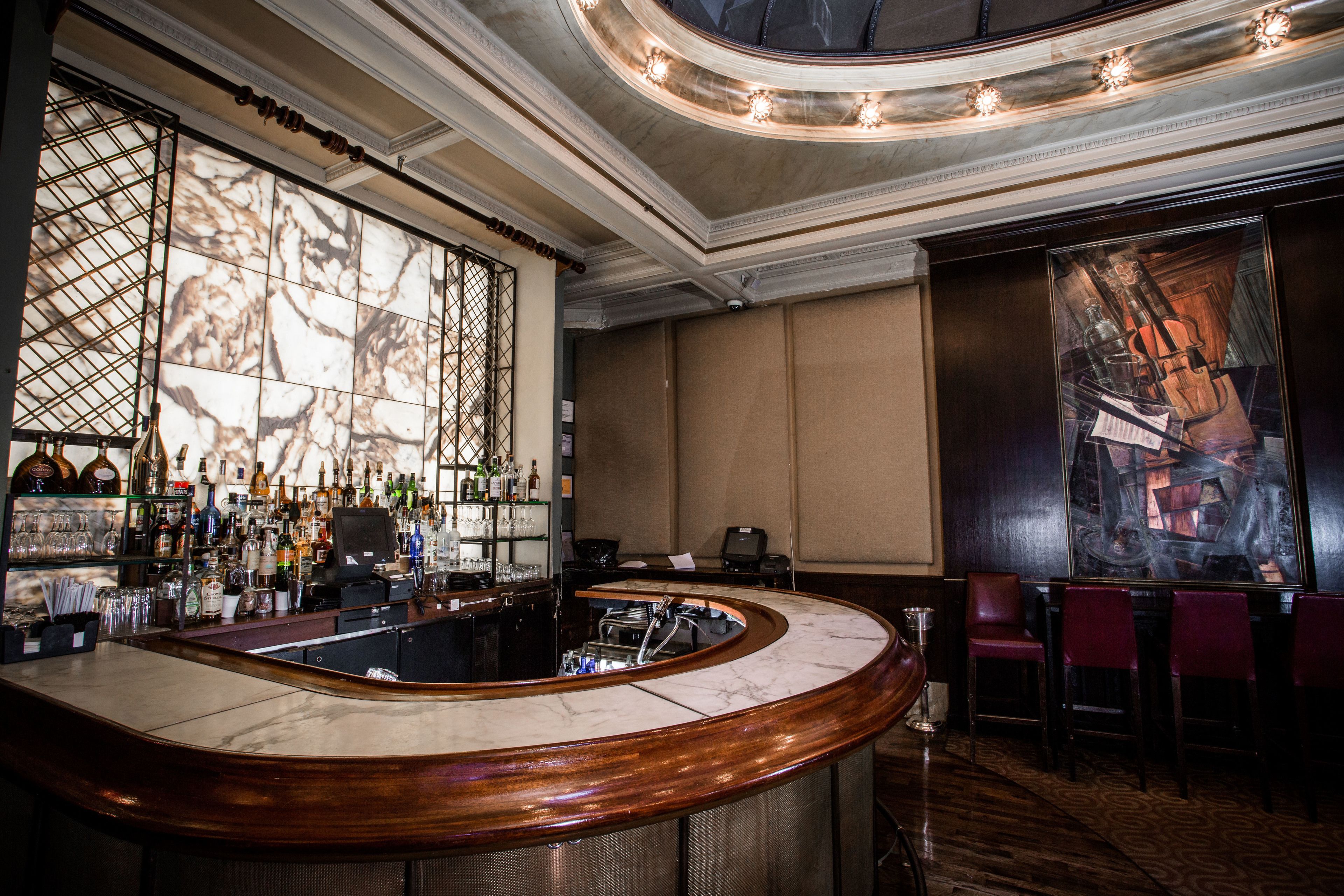 A bar area with a curved marble countertop, a wine rack with bottles, and a large window with a view of the city.
