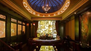 A bar area with a glass-top table, bar counter, and seating. - The Mansfield Hotel (New York)