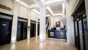 A hotel lobby with a reception desk, elevators, and a staircase. - The Mansfield Hotel (New York)