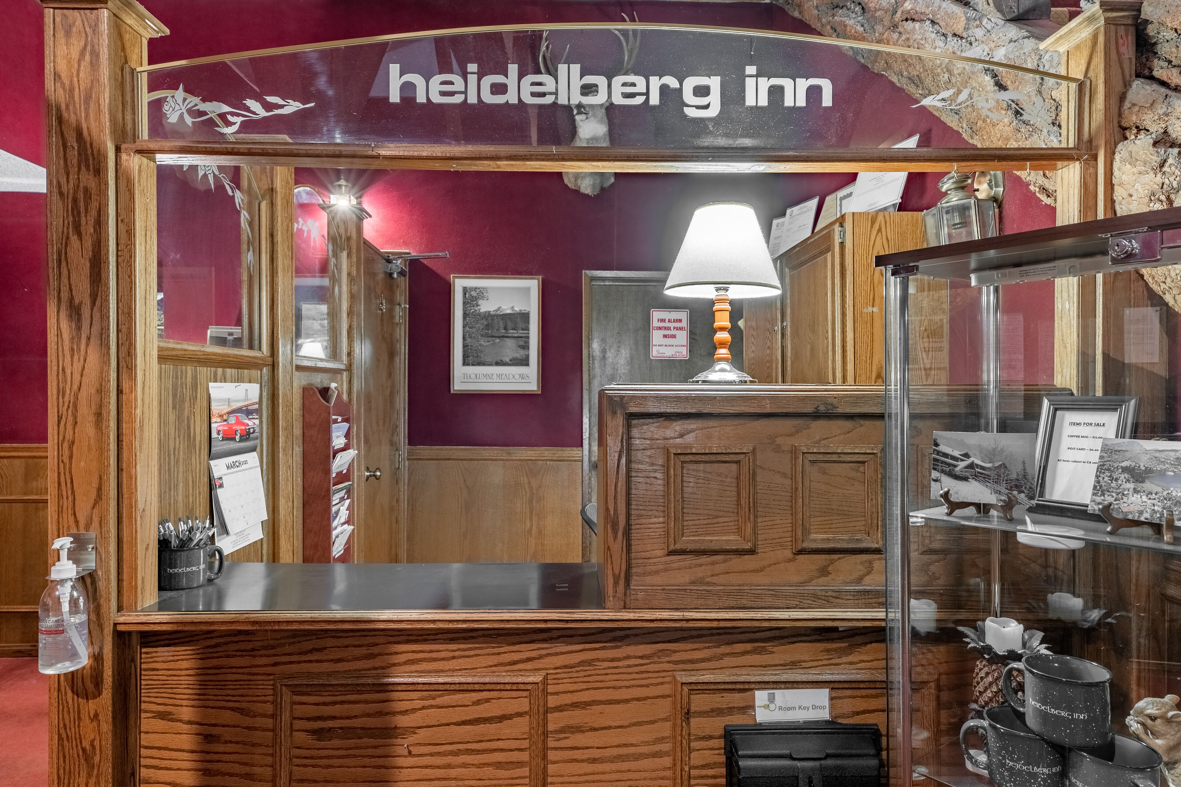 A reception desk with a wooden design, a sign reading "heidelberg inn," and a glass display case with items for sale.