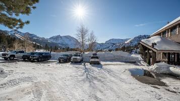 A snowy mountain road with parked vehicles and a building with a sloped roof.