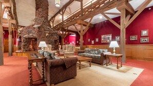 A spacious lobby with a stone fireplace, wooden beams, and red walls. - Heidelberg Inn (June Lake)