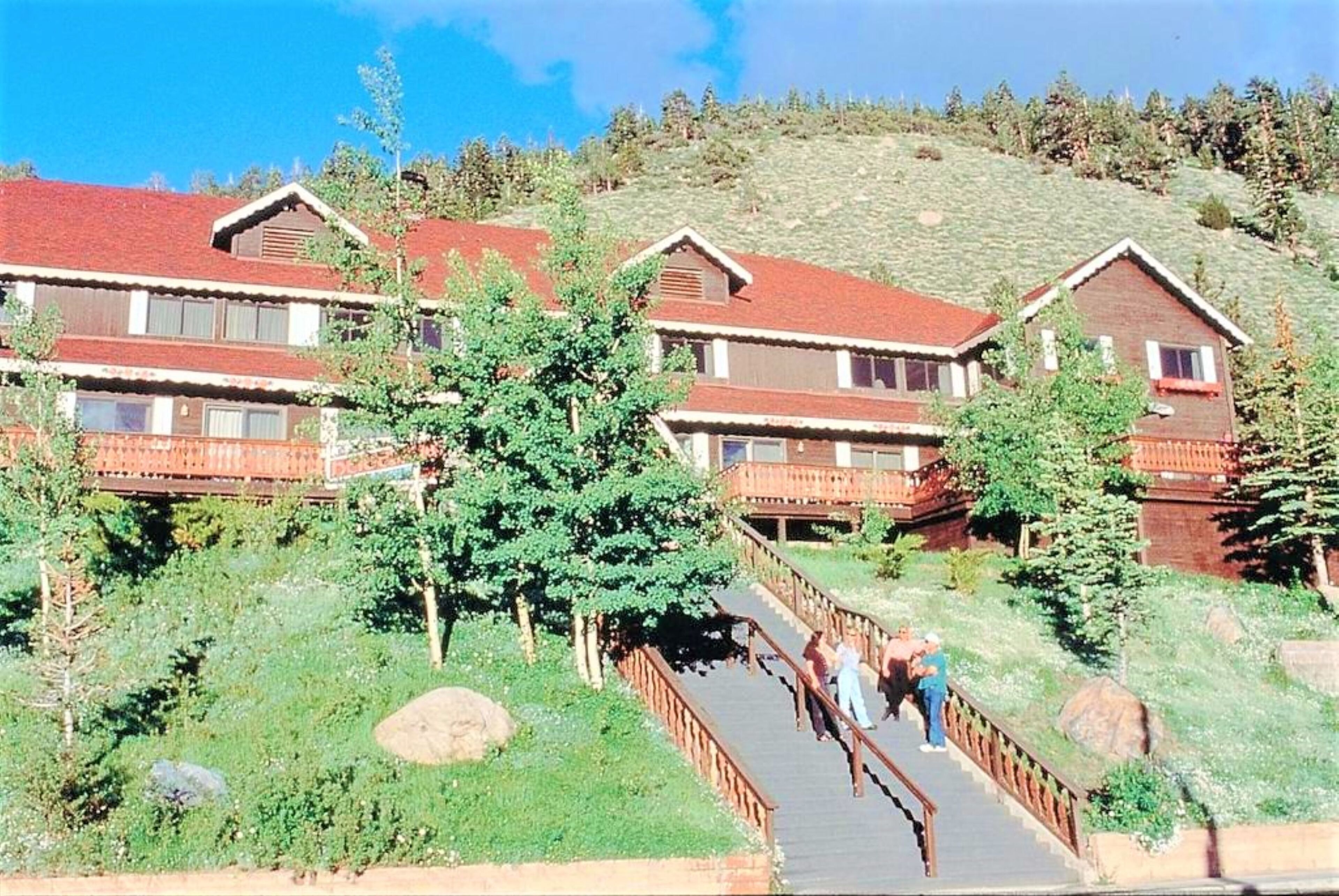 A lodge with multiple wooden buildings, a central staircase, and a surrounding natural landscape.