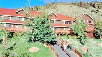 A lodge with multiple wooden buildings, a central staircase, and a surrounding natural landscape.