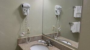 A bathroom with a sink, two hair dryers, a mirror, and a toilet. - Executive Inn (Schenectady)