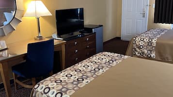 A hotel room with two beds, a desk with a TV, a chair, a dresser, and a door.