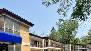 A motel with multiple floors, a covered entrance, and a parking lot. - Executive Inn (Schenectady)