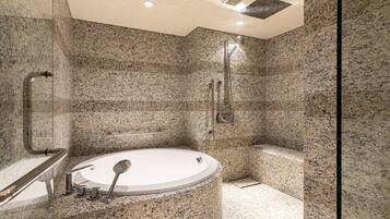 Un baño moderno con una bañera independiente, zona de ducha y paredes de granito.