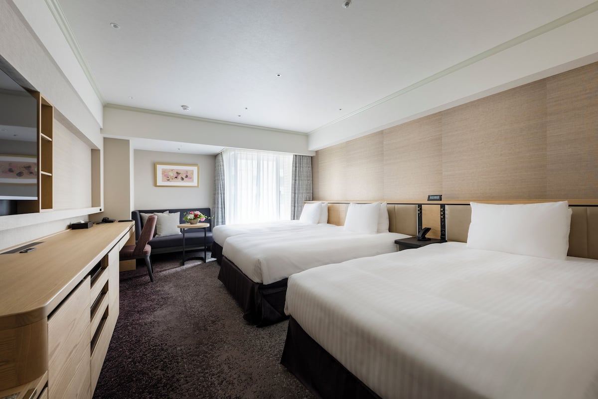 Une chambre d’hôtel avec deux lits, un bureau, une chaise et un grand miroir.