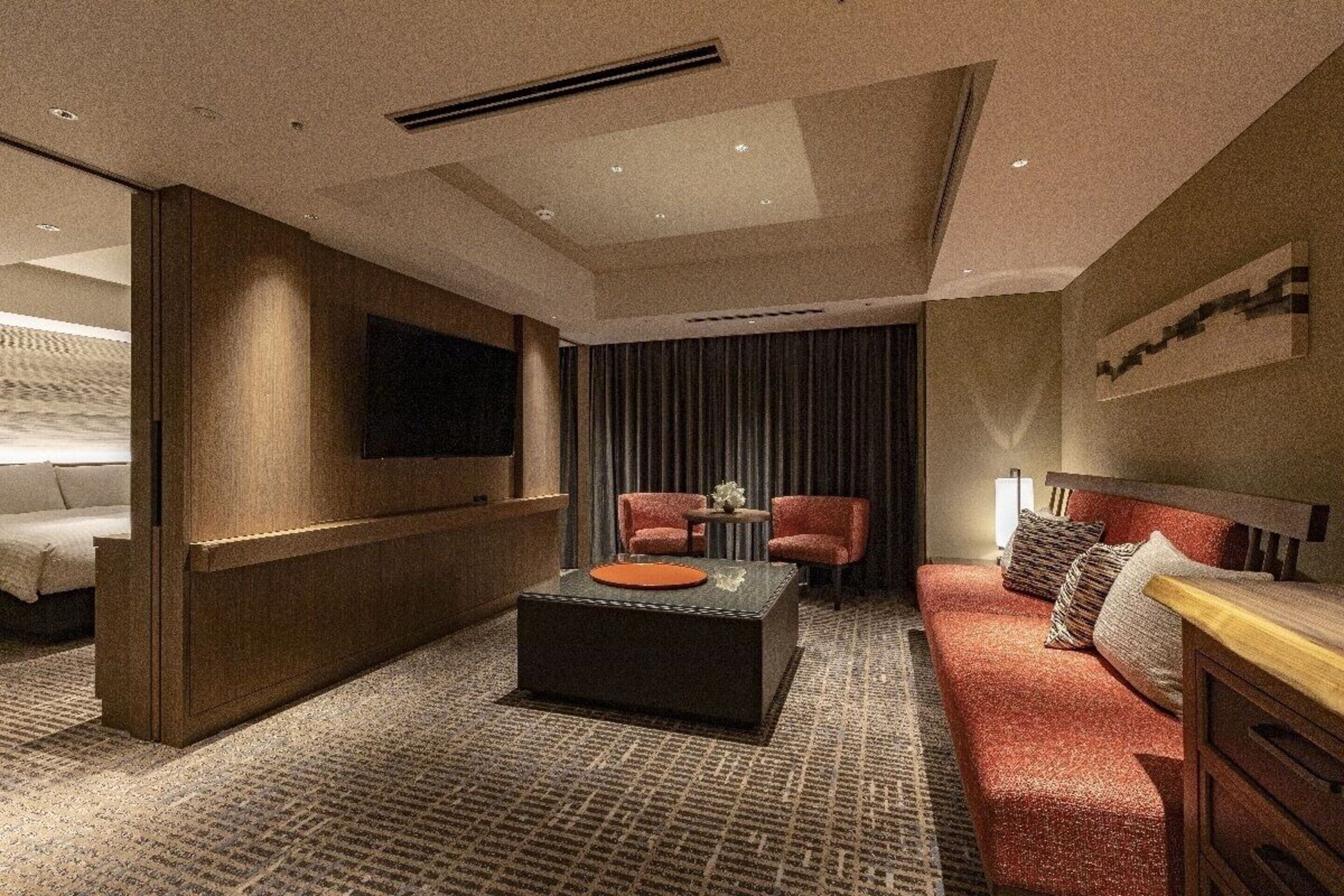 Een moderne hotelkamer met een groot bed, een bank, een salontafel en een aan de muur bevestigde televisie.