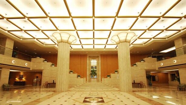 A spacious lobby with a high ceiling, large columns, and a central staircase. - Hotel Nikko Fukuoka (Fukuoka)