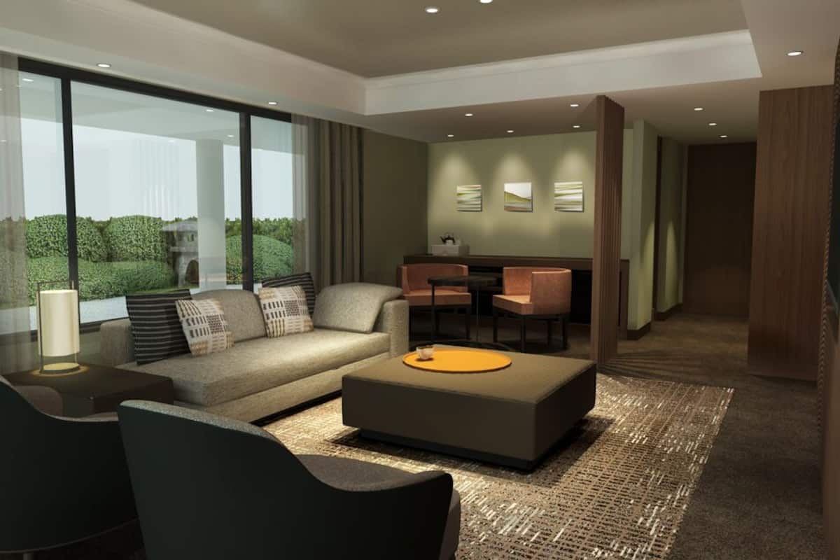 Une chambre d’hôtel moderne équipée d’un canapé, de fauteuils, d’une table basse et d’un coin repas.