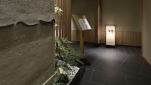 A hallway with a stone wall, wooden beams, a signboard, and a tiled floor. - Hotel Nikko Fukuoka (Fukuoka)
