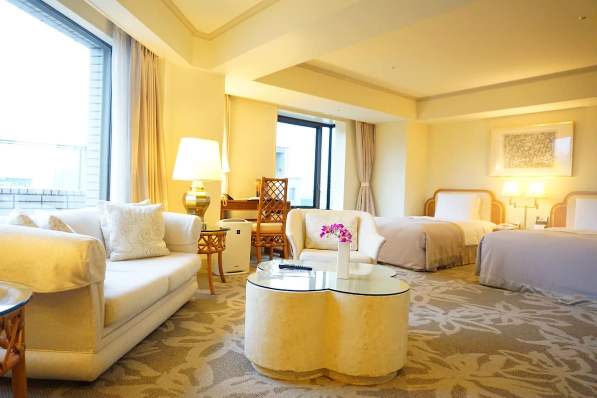 Une chambre d’hôtel avec deux lits, un canapé, une table basse et un bureau.