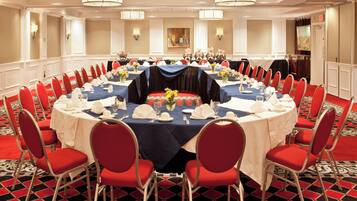A conference room with round tables, red chairs, and a patterned carpet.