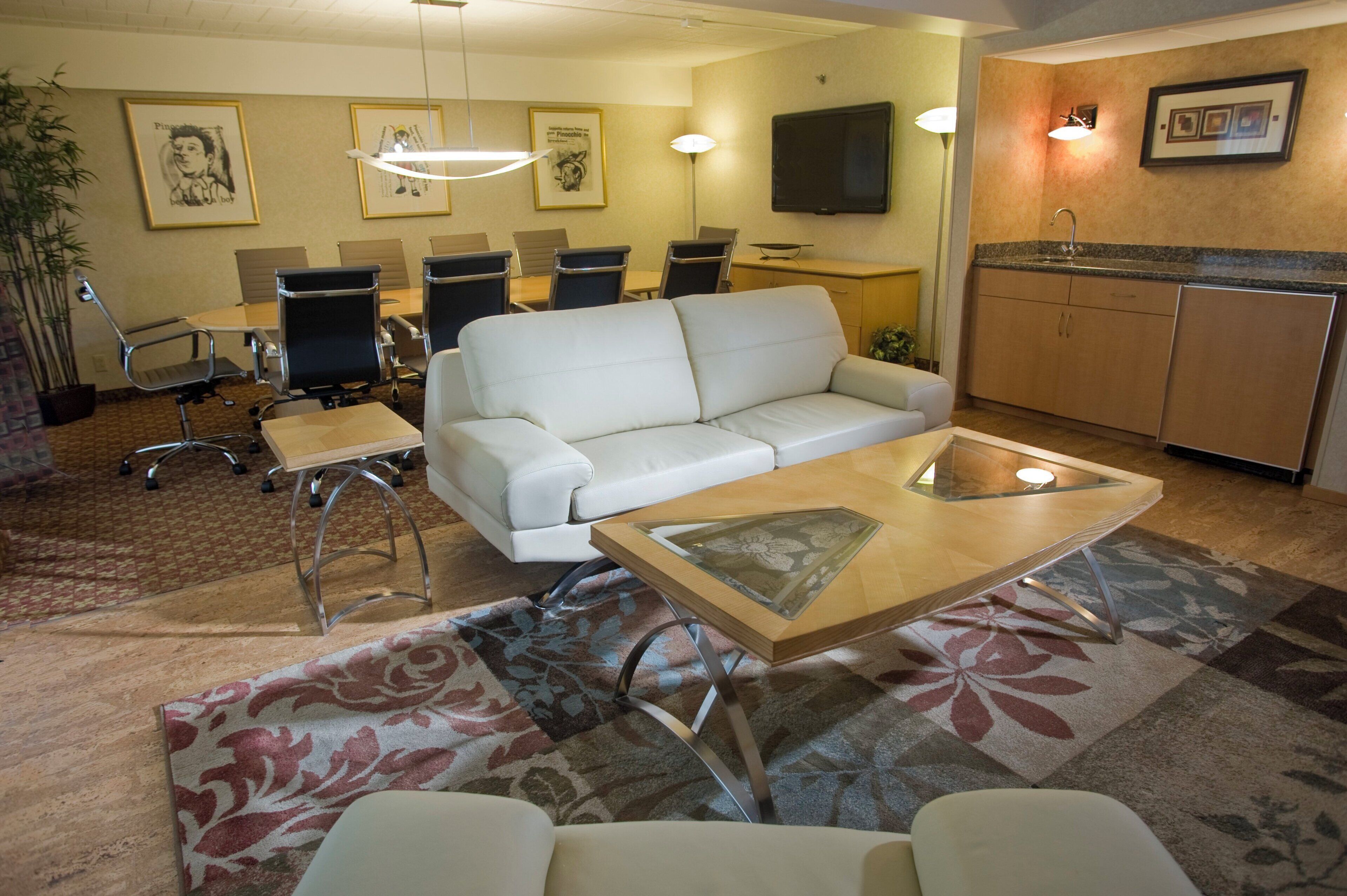 Een hotelkamer met een bank, een tafeltje, een televisie, een bureau en een stoel.