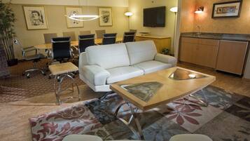 Een hotelkamer met een bank, een tafeltje, een televisie, een bureau en een stoel.
