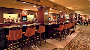 Eine Bar mit mehreren Sitzplätzen und einer Theke, die mit Flaschen bestückt ist.