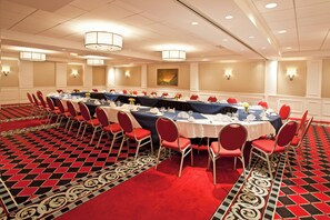 A conference room with round tables, red chairs, and a patterned carpet. - Holiday Inn Johnstown Downtown by IHG (Johnstown)