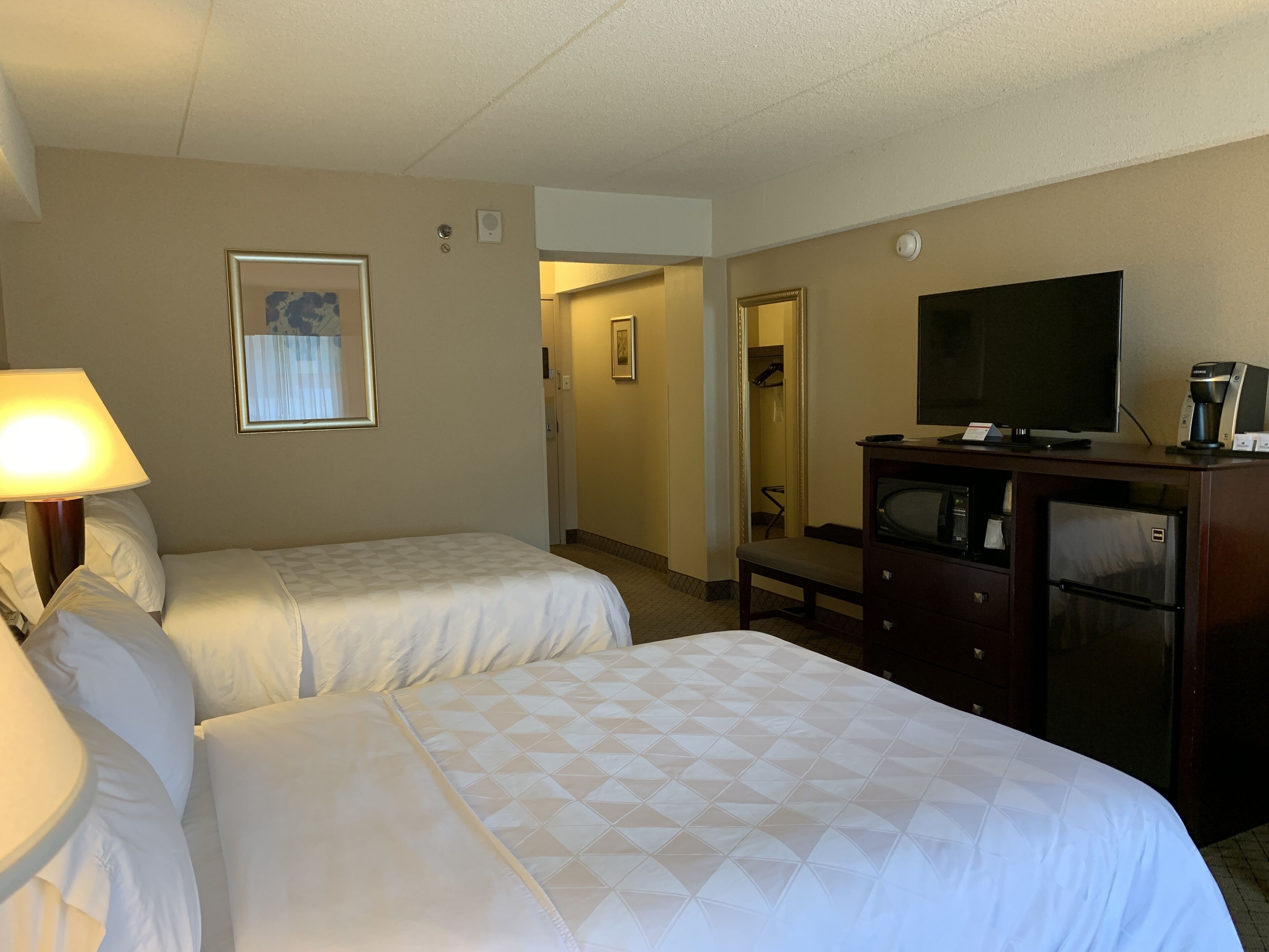 Una habitación de hotel con dos camas, televisión, cafetera y cómoda.